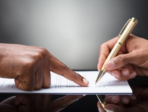 Business Borrowing Concept – Finger Pointing In Front Of A Person Signing With Golden Pen On The Document