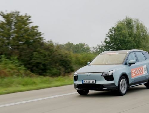 Blue electric SUV (Model Aiways U5) car driving on the road/Autobahn with greenery in the background