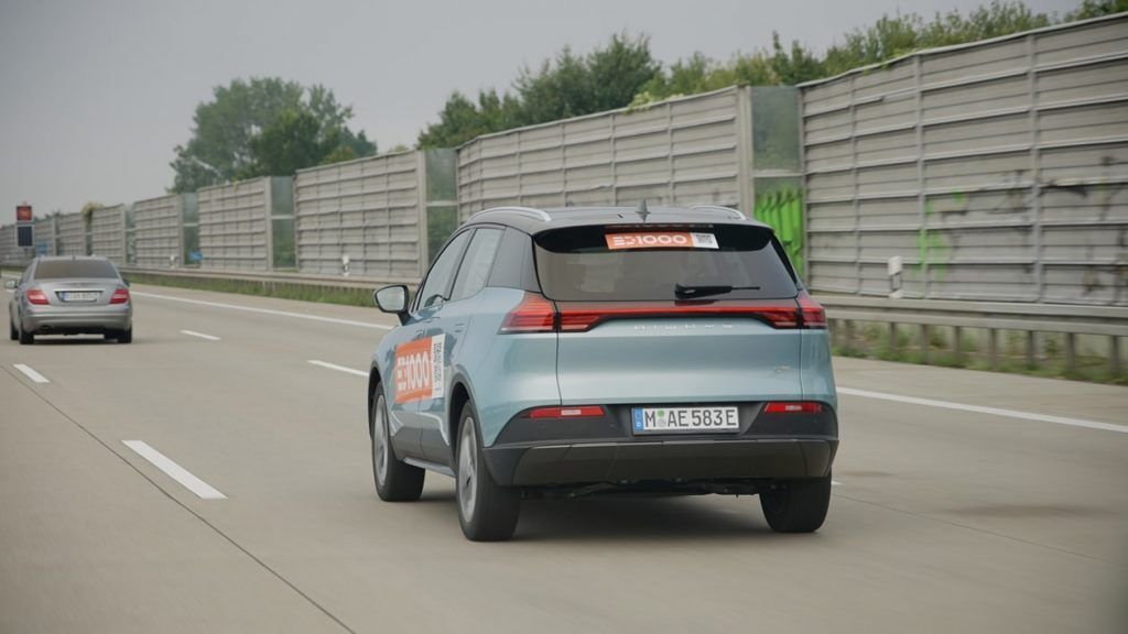 Rear end view of blue electric SUV driving on the autobahn